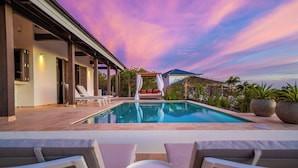 A swimming pool with lounge chairs and a covered seating area. - Kas Ubuntu - Villa with Panoramic Ocean Views (Kralendijk)