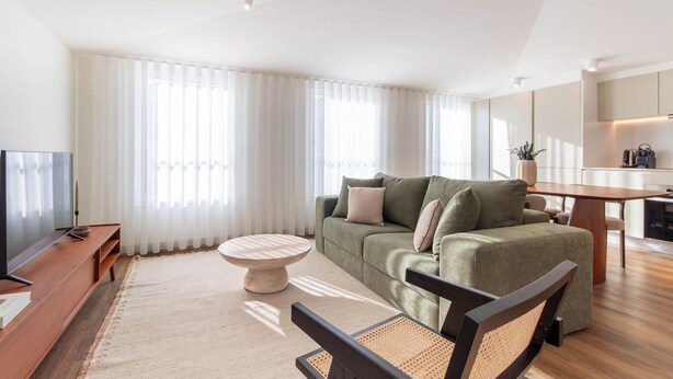 Ett modernt vardagsrum med en soffa, ett soffbord, en tv och en matplats.