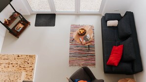 A living room with a dark sofa, a chair, a wooden coffee table, a striped rug, and a window with a view of the outside.