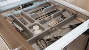 A kitchen drawer with utensils and a coffee maker.