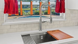 A kitchen with a window, a sink, and a wooden cutting board.