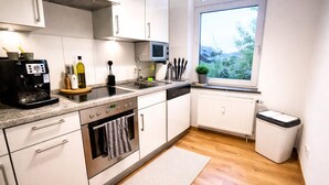Una cucina moderna con forno integrato, macchina per caffè, lavandino e finestra vista sul verde.