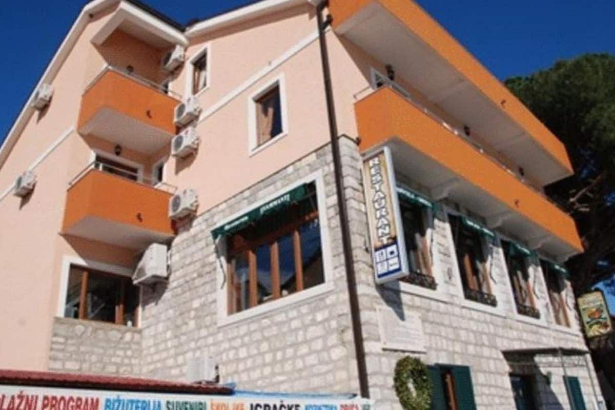 Un edificio de varios pisos con un letrero de restaurante, balcones y fachada de piedra.