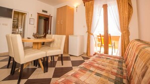 A compact room with a bed, a dining table with chairs, a small refrigerator, and a kitchenette area. - Fiammanti Hotel Montenegro (Denovici)