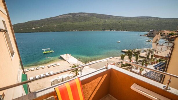 A balcony with a view of a beach, a pool, and a mountain. - Fiammanti Hotel Montenegro (Denovici)