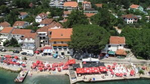 Luftaufnahme einer Küstenstadt mit Strand, roten Sonnenschirmen und einem Pier.