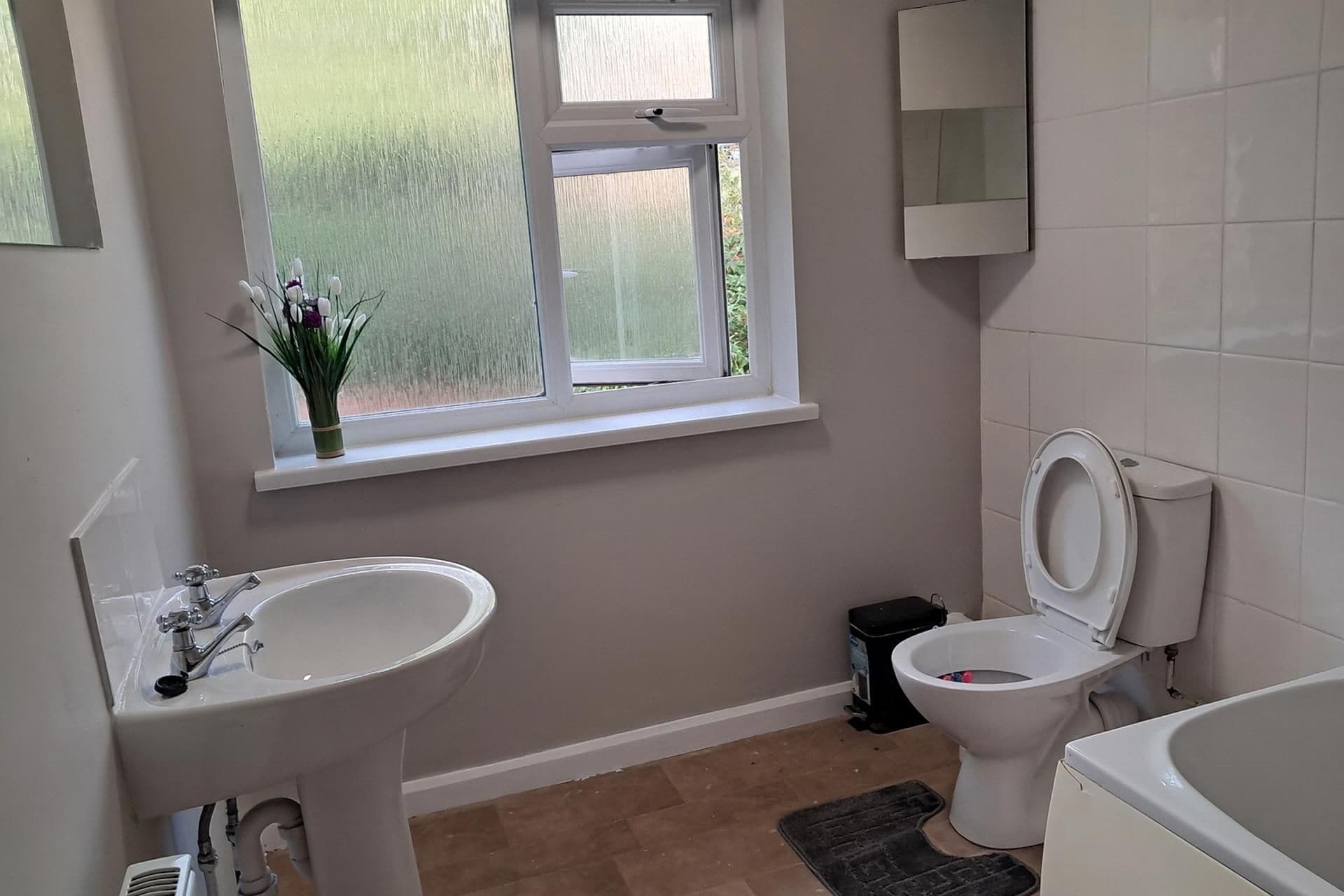 Ein Badezimmer mit Fenster, Waschbecken, Toilette und Badewanne.