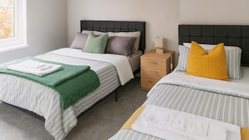 A hotel room with two beds, a bedside table, and a nightstand.