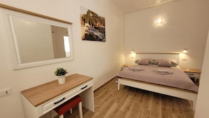 A bedroom with a bed, bedside tables, a desk, a chair, a mirror, and a wall-mounted picture. - Sunset Bay Villa Kevin (Orebic)