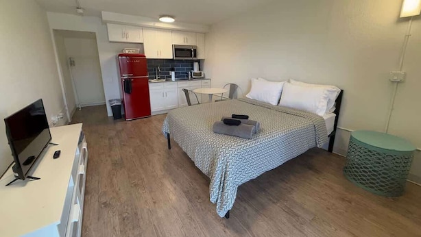 A compact room with a bed, a small kitchenette, a TV, and a trash bin. - [10] Resort Pool & Gym Access in Central Austin Studio (Austin)