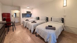 Een kamer met drie bedden, een kitchenette en een eethoek.