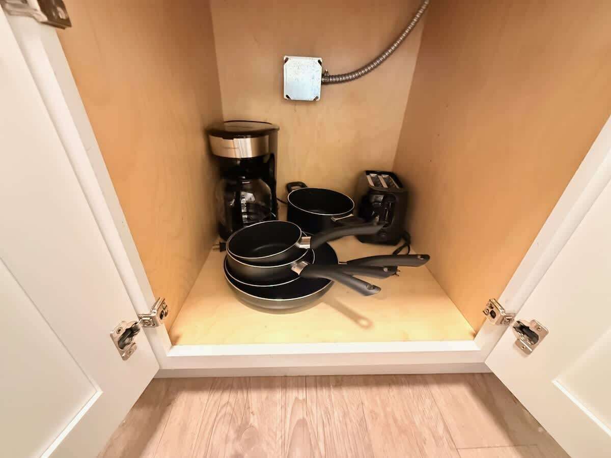 A compact kitchen with a coffee maker, a toaster, and a frying pan.