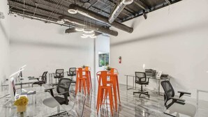 A conference room with a glass table, black and orange chairs, and a visible fire extinguisher. - [27] ATX Studio: 2 Twin Beds, Pool, Gym & Dog Park (Austin)