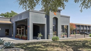 A modern building with a large entrance, a parking area, and a small garden with plants. - [27] ATX Studio: 2 Twin Beds, Pool, Gym & Dog Park (Austin)