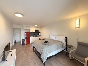A compact room with a bed, a small table, a sofa, a kitchenette, and a TV. - [44] ATX Studio: 1 Queen, Access to Gym & Laundry (Austin)