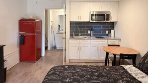 A compact kitchen with white cabinets, a red refrigerator, and a microwave. - [01] ATX Studio: 1 King, Dog Park, Laundry Access (Austin)