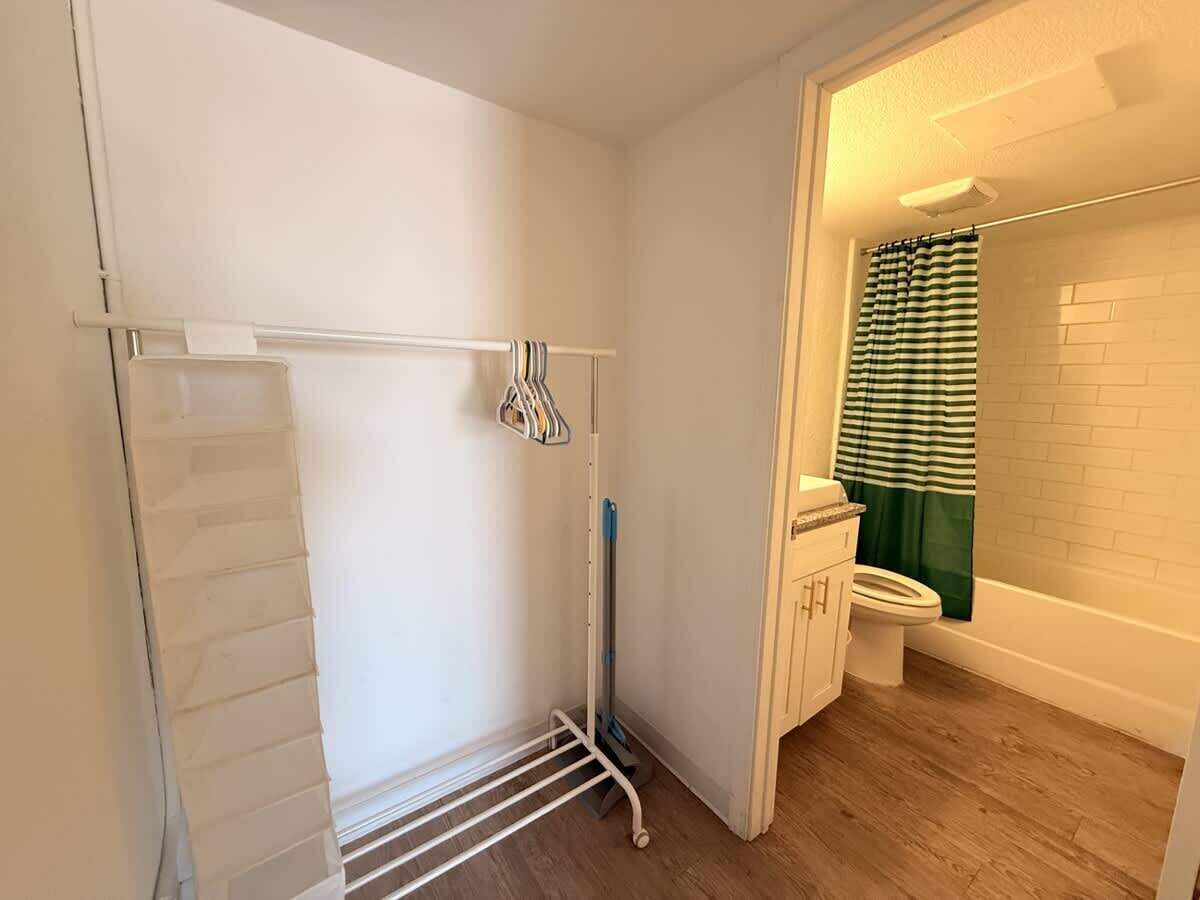 A small bathroom with a shower, toilet, and a metal drying rack.