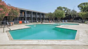 A swimming pool with a 3-foot depth, surrounded by lounge chairs and a building with balconies. - [02] ATX Studio: 1 Queen, Dog Park, Laundry Access (Austin)