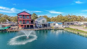 A waterfront property with a two-story building, a dock, and a fountain. - N125:  Lakefront 3br/2ba Home in Ocean Lakes - "Sandy Cove" (Myrtle Beach)