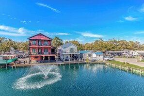 A waterfront property with a two-story building, a dock, and a fountain. - N125:  Lakefront 3br/2ba Home in Ocean Lakes - "Sandy Cove" (Myrtle Beach)