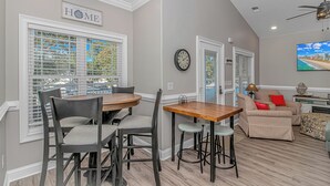 A dining area with a round table and chairs, a sofa, a clock, and a TV. - N125:  Lakefront 3br/2ba Home in Ocean Lakes - "Sandy Cove" (Myrtle Beach)