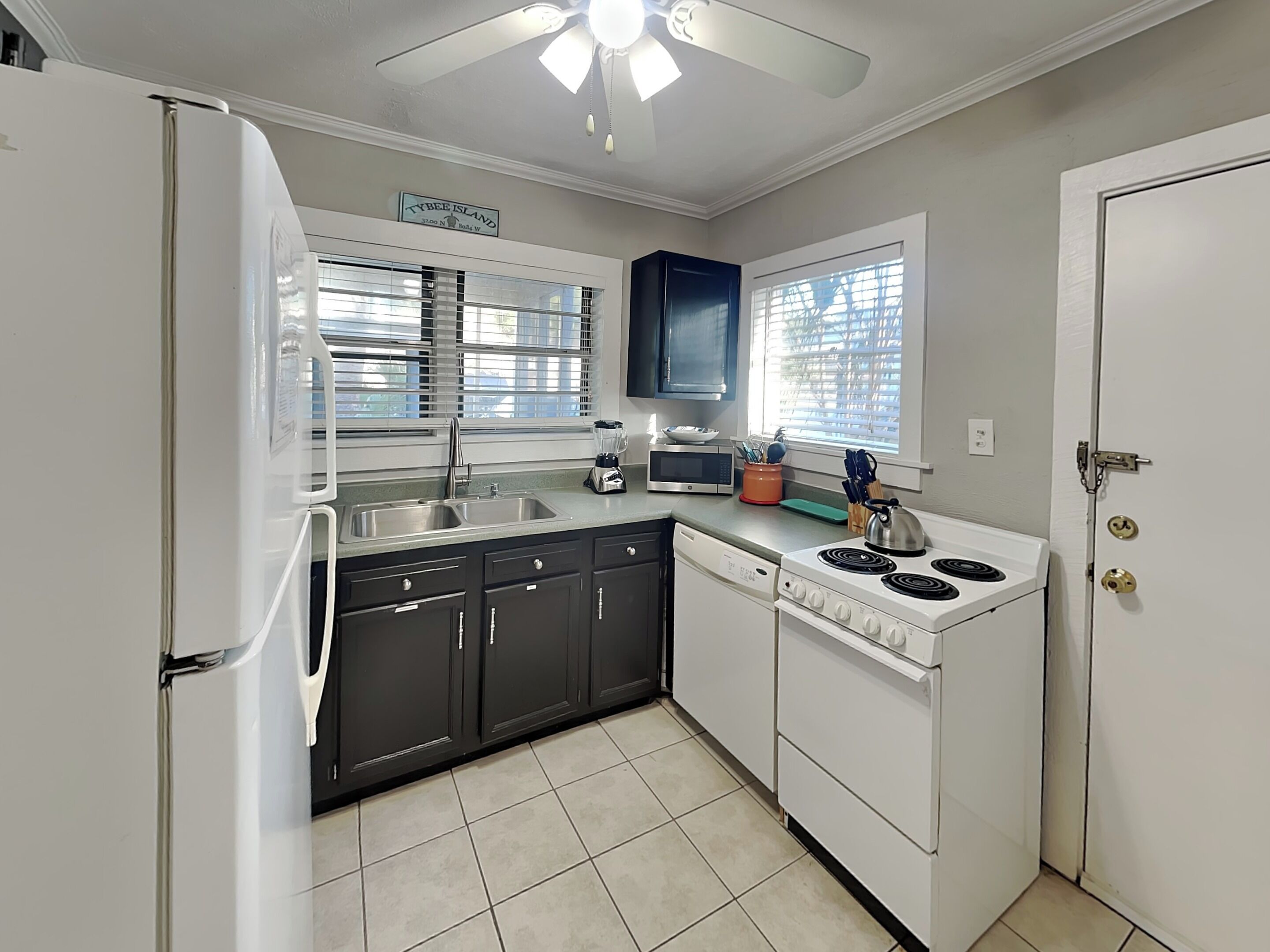 A kitchen with a refrigerator, stove, microwave, sink, and cabinets.