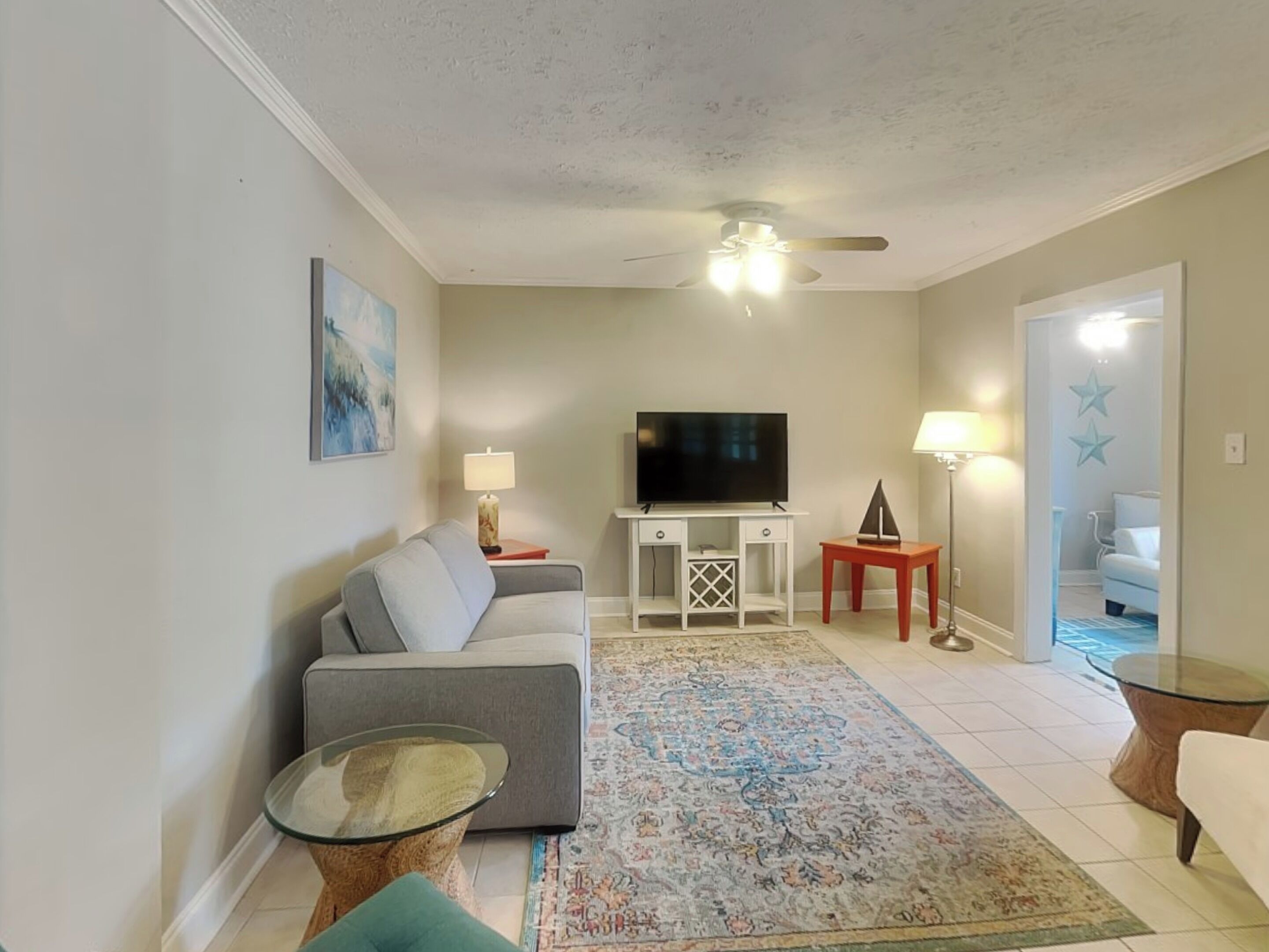 A living room with a sofa, TV, and a ceiling fan.