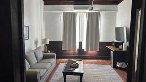 Ein Wohnzimmer mit Sofa, Couchtisch, Fernseher und Deckenventilator.