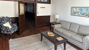 Ein Wohnzimmer mit einer Couch, einem Sessel, einem Couchtisch, einer Lampe und einem Bild an der Wand.
