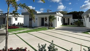 Una casa moderna con un molino, un césped bien cuidado y un cielo azul despejado.
