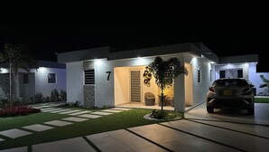 Una casa moderna con entrada iluminada, un camino de acceso y un automóvil.