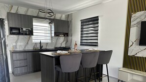 Una cocina moderna con una isla central, taburetes de bar y un microondas integrado.