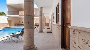 A poolside area with lounge chairs, a pool, and a building with columns and a wooden door. - Casa Nacho Hotel by Monyxbnb (Puerto Vallarta)