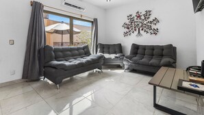 A modern living room with a grey sofa, a smaller grey armchair, and a wooden coffee table. - Casa Nacho Hotel by Monyxbnb (Puerto Vallarta)