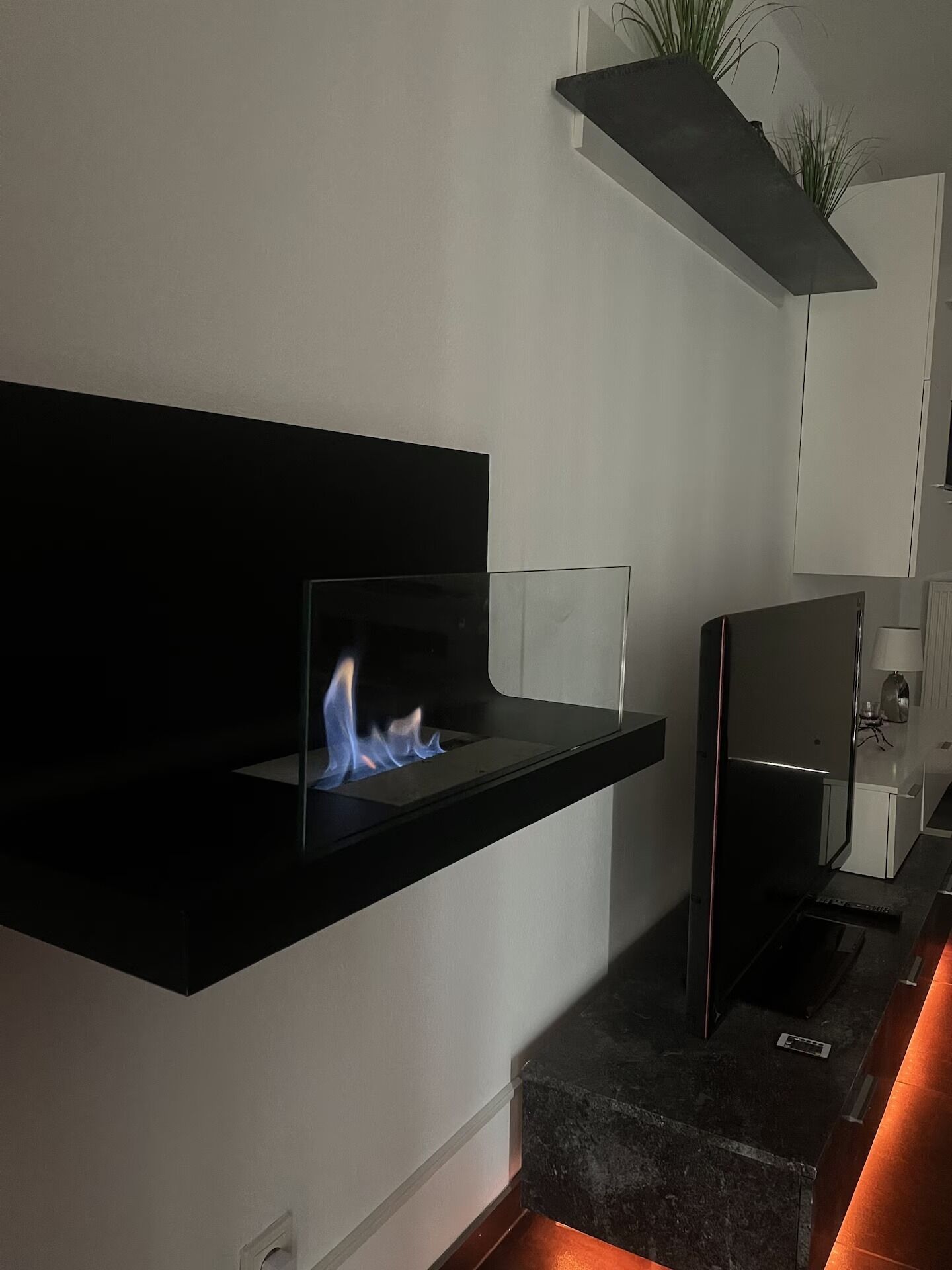 Eine moderne Küche mit schwarzem Arbeitsplatz, einer Glasrückwand und einer sichtbaren Flamme.