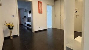 A modern hallway with dark flooring, a vase with flowers, and a geometric light fixture. - Modern 3 room apartment | subway fair | parking lot (Fürth)