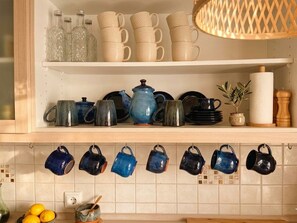 A kitchen with shelves holding various mugs and a hanging rack with mugs. - House Kipos: Where your cell phone battery lasts longer than your worries (Malonas)