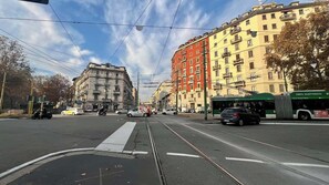 A street with tram tracks, buildings, and a green bus. - Novo apartment Island (Milano)