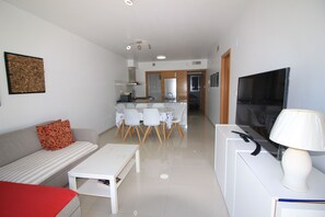 A modern living room with a sofa, a coffee table, a TV, and a dining area with chairs and a table. - Groundfloor Varudi Aguas Nuevas, Torrevieja (Torrevieja)