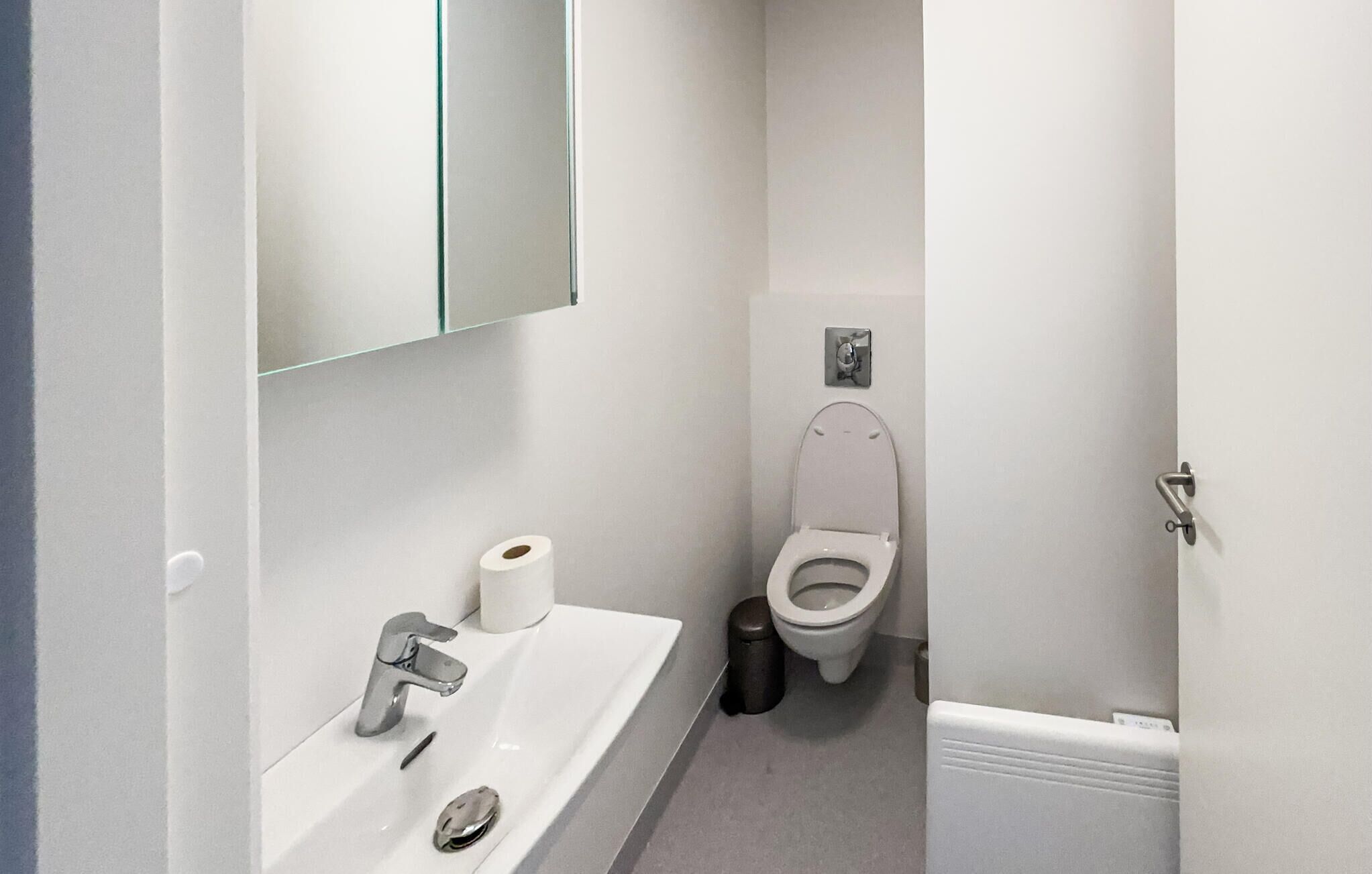 A small bathroom with a white sink, toilet, and a mirror.