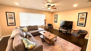 Ein Wohnzimmer mit Sofa, Couchtisch, Fernseher und Bildern an den Wänden.
