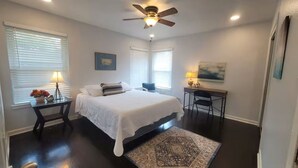 Ein Schlafzimmer mit Bett, Schreibtisch, Stuhl, Deckenventilator und Teppich.