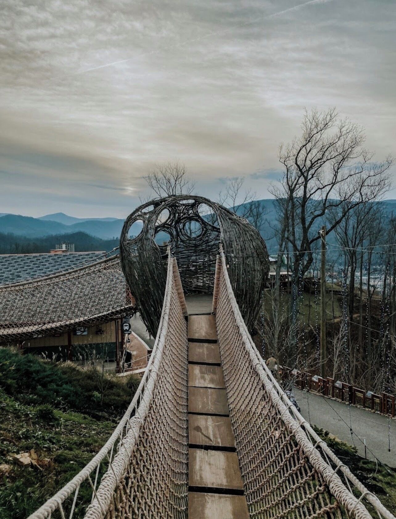 Un puente colgante que conduce a una edificación tradicional con una estructura de techo circular.