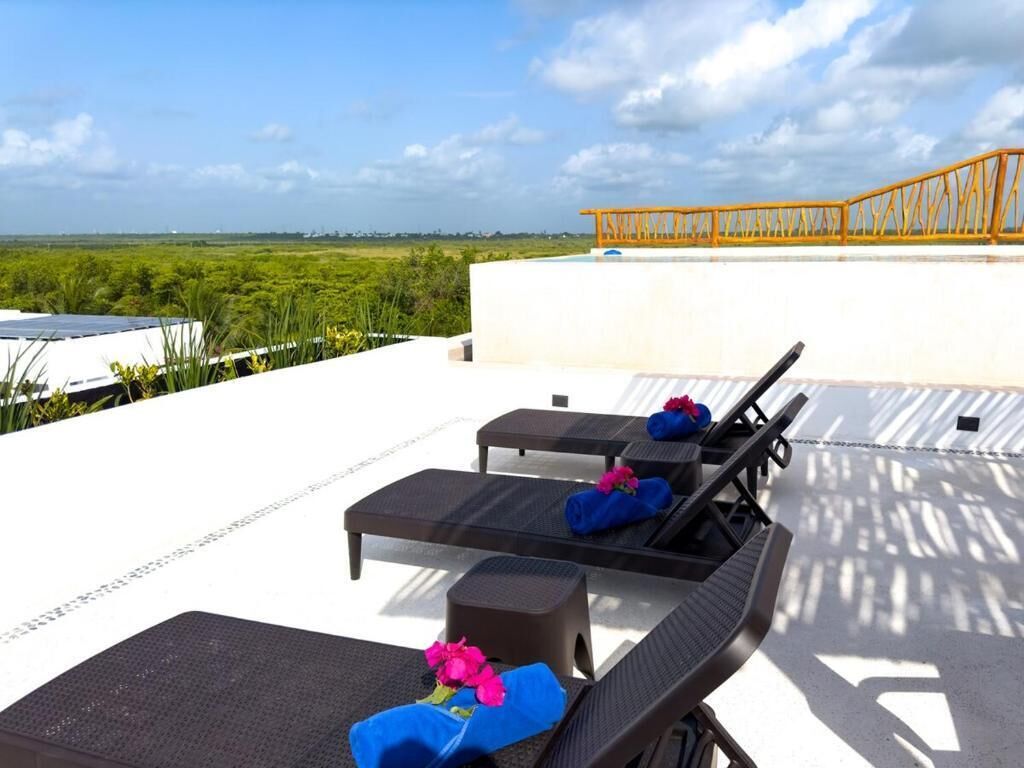Une terrasse sur le toit, avec des chaises longues, une petite table et une vue sur le paysage.