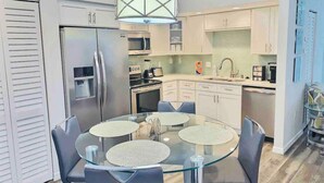 A modern kitchen with a glass dining table, stainless steel appliances, and light-colored cabinetry. - Near Beaches & IMG Academy, Mins to Downtown (Bradenton)