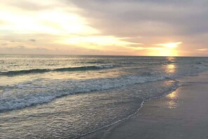 Uma praia com ondas e um pôr do sol.
