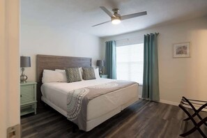 A bedroom with a bed, a ceiling fan, a nightstand, a lamp, a chair, and a window with curtains. - Near Beaches & IMG Academy, Mins to Downtown (Bradenton)