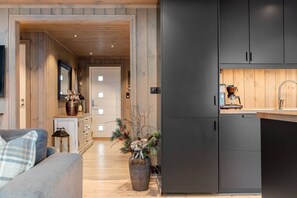 A modern kitchen with dark cabinets, a wooden countertop, and a coffee machine.