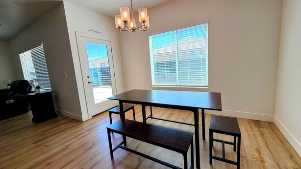 A spacious room with a large dining table, benches, and a chandelier. - Spacious 4BR in Red Trails 30+ Day Stays (Washington)