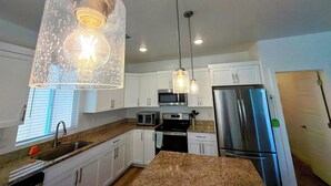 A modern kitchen with white cabinets, stainless steel appliances, granite countertops, and pendant lighting. - Spacious 4BR in Red Trails 30+ Day Stays (Washington)
